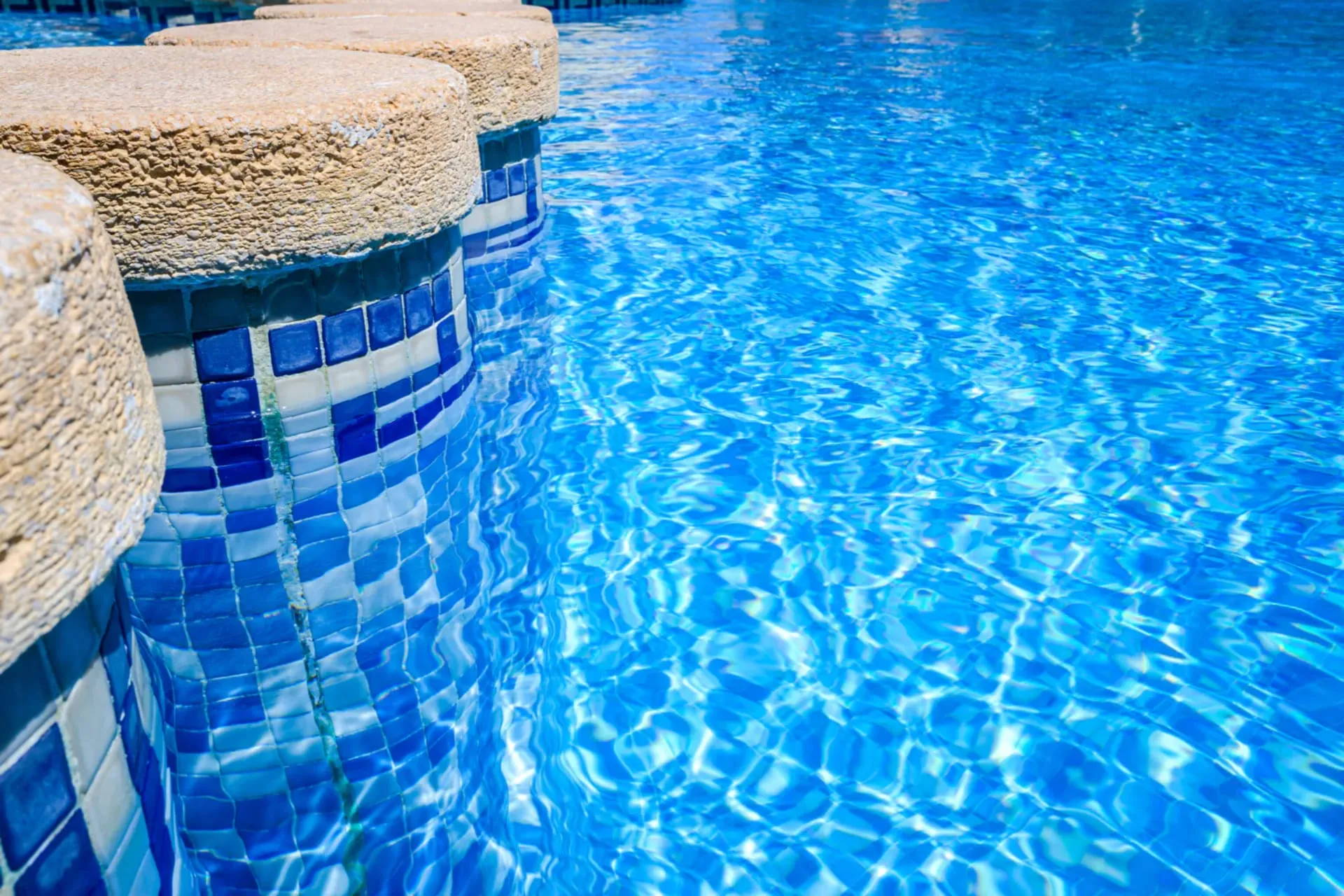 Mosaic tile steps leading into clear pool water